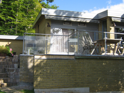 Terrasse læhegn, læskærm i glas monteret direkte på terrasse belægning med rustfrie balystre og glasbeslag.