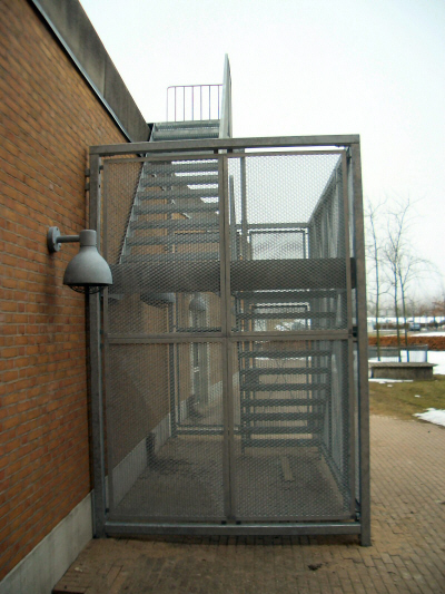 Ligeløbs-trappe aflåselig: Galvaniseret ligeløbs-trappe, med trappetrin af gitterriste. Stålbur beklædning af varmtgalvaniseret strækmetal.