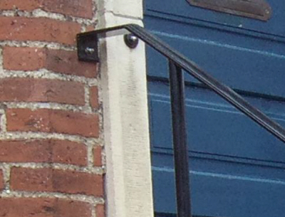 Helt-enkelt sort Smedejerns gelænder: Fastgøring i mur + trappetrin m. limankre.
